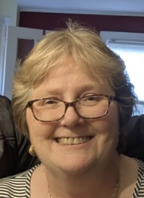 A woman with glasses smiling for the camera.
